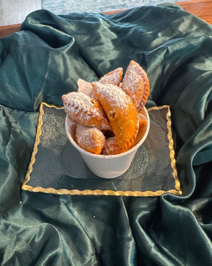 A cup of Peaches & Cream mini empanadas dusted with powdered sugar